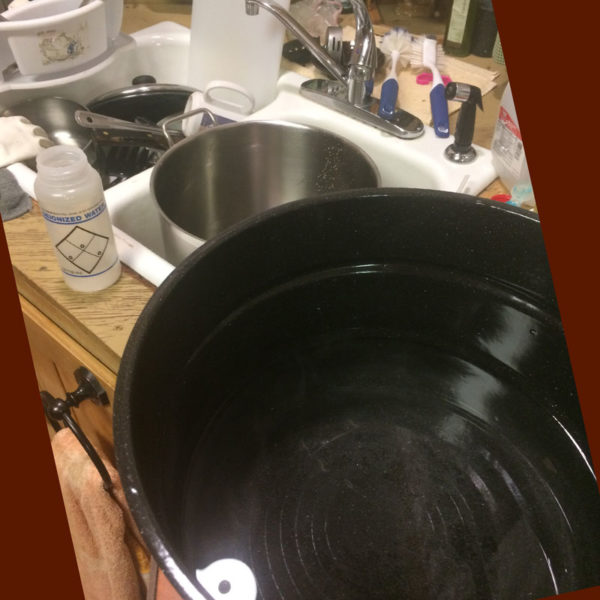 The large pot of heated water, the washing pot, and the dirty dishes that need to be pre-rinsed.