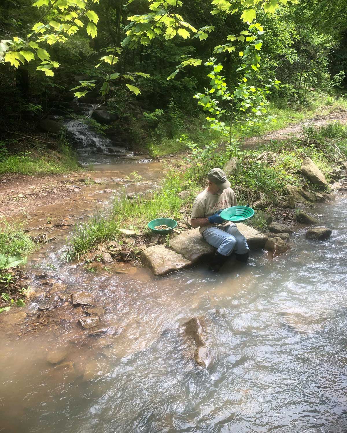 Panning for gold with Colorado soil in an Ozark nature artist's creek.