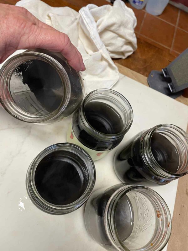 After grinding charred bones and washing the pigment, pour the colored water into jars. Wash at least twice, use as many jars as needed to pour off the water.